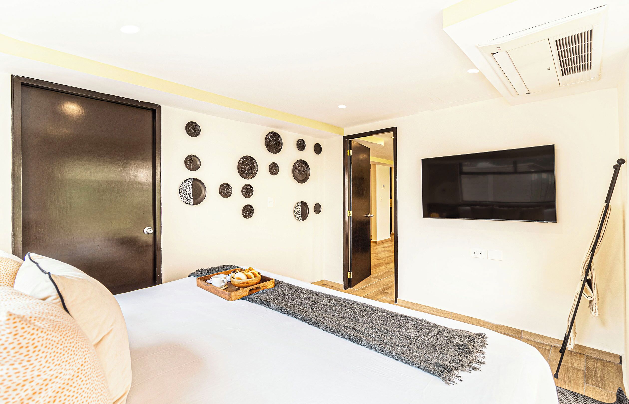 A hotel room with a bed, a TV mounted on the wall, and a door leading to another room.