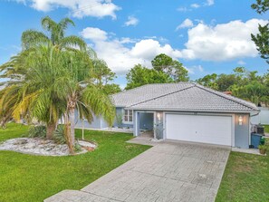 A single-story house with a tiled roof, a garage, and a well-maintained lawn.