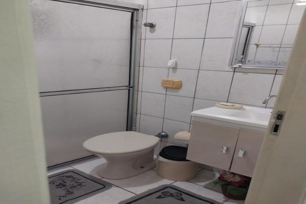 A small, compact bathroom with a toilet, sink, and mirror.