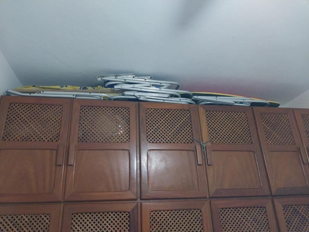A wooden cabinet with perforated panels and a stack of folded items on top.