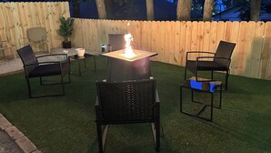 Eine Terrasse im Freien mit Tisch und Stühlen, einem Feuerkorb und Lichterketten.