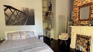 A bedroom with a bed, a fireplace, a mirror, and a bookshelf. - Cozy studio in enchanting New Orleans Neighborhood with AC, WiFi (New Orleans)