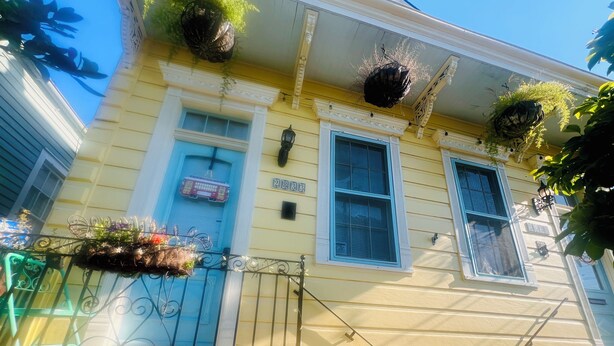 A yellow building with a blue door and windows, a number '2883' on the wall, and hanging planters with greenery. - Cozy studio in enchanting New Orleans Neighborhood with AC, WiFi (New Orleans)