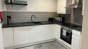 A modern kitchen with a black countertop, white cabinets, a stainless steel range hood, and a microwave. - Location, Location, city centre apartment, 2 bedrooms, 2 bathrooms (Liverpool)