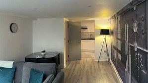 A modern living room with a sofa, a small round table, and a clock on the wall. - Location, Location, city centre apartment, 2 bedrooms, 2 bathrooms (Liverpool)