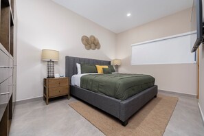 Une chambre à coucher comprenant un lit, deux tables de chevet, un élément décoratif fixé au mur et une grande fenêtre.