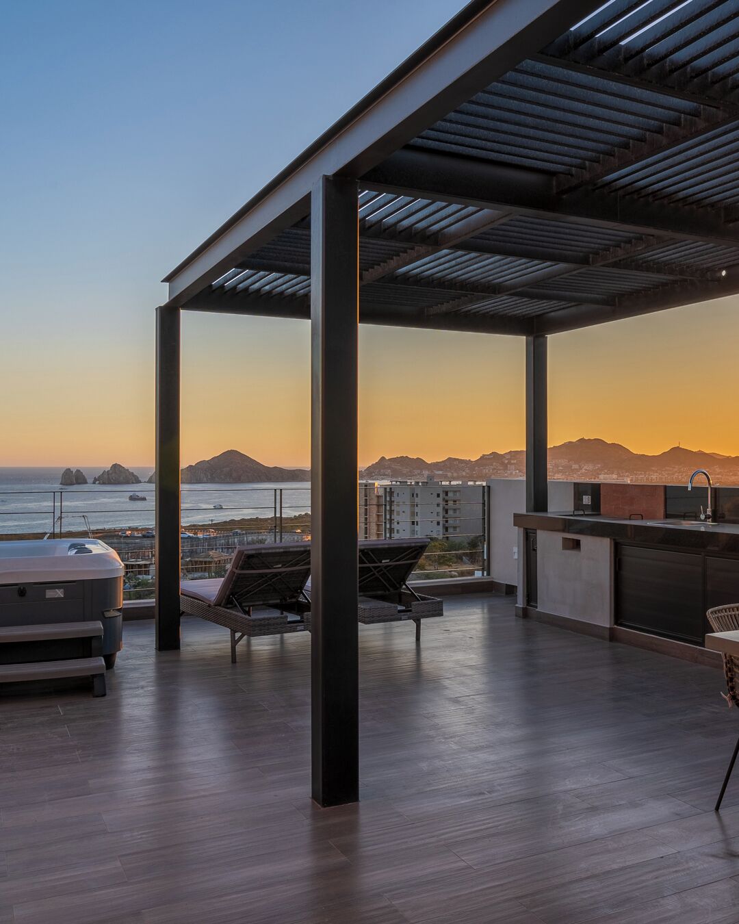 Terraza en la azotea con vistas al océano y las montañas, que cuenta con una zona de bar y asientos.