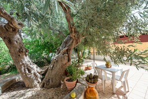 An outdoor seating area with a table and chairs, surrounded by olive trees and potted plants. - Villa Rosa by Rentbeat (Montalbano di Fasano)