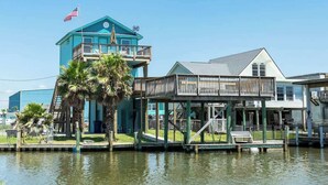 A waterfront building with a blue exterior, a balcony, and a flag. - Fisherman Dream Waterfront Home with Private Dock (Surfside Beach)