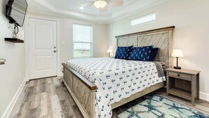 A bedroom with a bed, a nightstand, a TV mounted on the wall, a ceiling fan, and a door. - Fisherman Dream Waterfront Home with Private Dock (Surfside Beach)