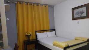 A single bed with a wooden frame, a bedside table with a vase of flowers, and a chair. - Miss. Emily Place (Monrovia)