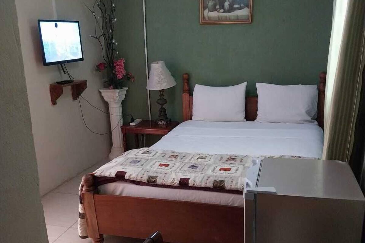 A hotel room with a bed, a TV, a table, and a chair.