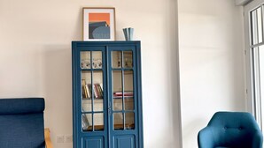 A room with a blue cabinet, a blue armchair, and a wooden table.