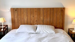A bed with a wooden headboard, white bedding, and two bedside lamps.