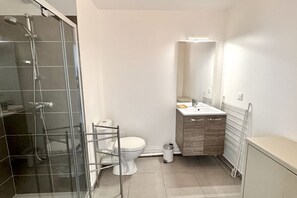 Ein modernes Badezimmer mit Duschkabine aus Glas, einer weißen Toilette, einem Holzbadezimmermöbel und einem Spiegel über dem Waschbecken.