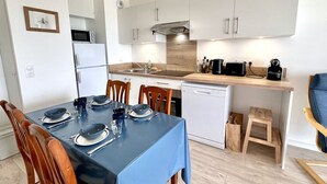 A modern kitchen with white cabinets, a microwave, a dishwasher, and a coffee maker.