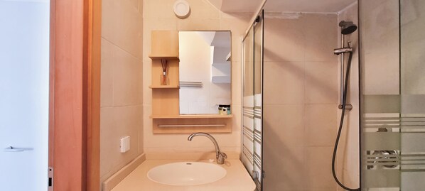 Une salle de bain moderne avec un lavabo, un miroir et une douche.