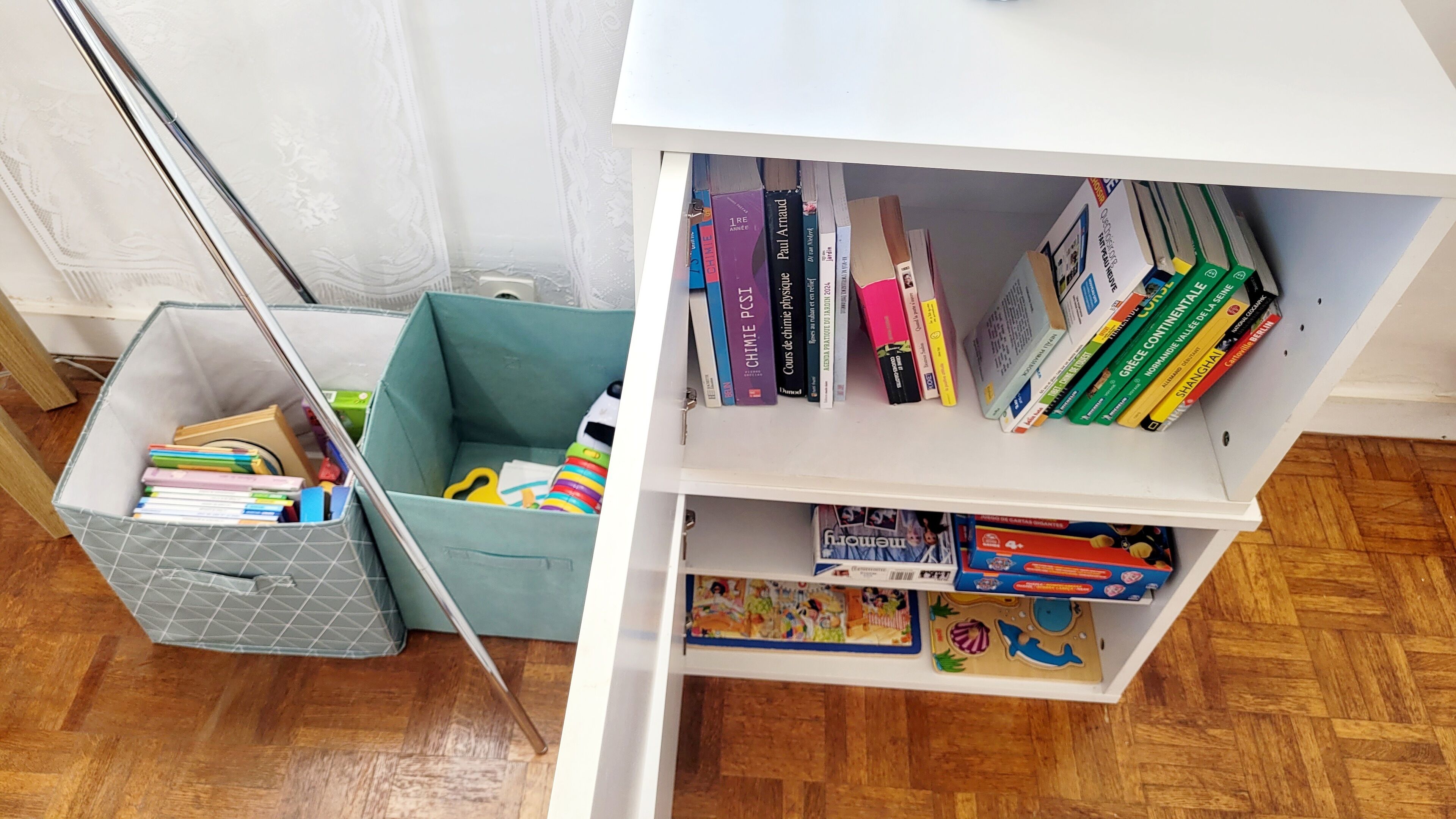 A bookshelf with various books and a toy box.