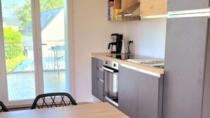 A modern kitchen with a dining table, chairs, and a built-in oven. - House 4 Bdrms and Terrace, Garden near. Sea, Golfs, Salt marshes, Walks (Guérande)