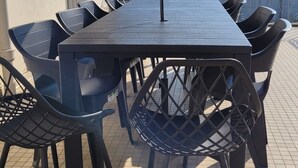 An outdoor dining area with a table and chairs, an umbrella, and a stone building in the background. - House 4 Bdrms and Terrace, Garden near. Sea, Golfs, Salt marshes, Walks (Guérande)