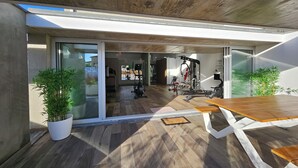 A modern home gym with exercise equipment, a wooden table, and potted plants. - Marinha Grande Apartament GREEN LOFT N°6 (Marinha Grande)