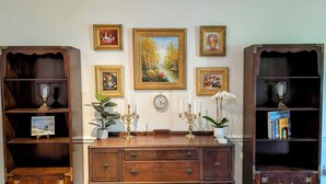 Una habitación con un armario de madera, estanterías y cuadros en la pared.