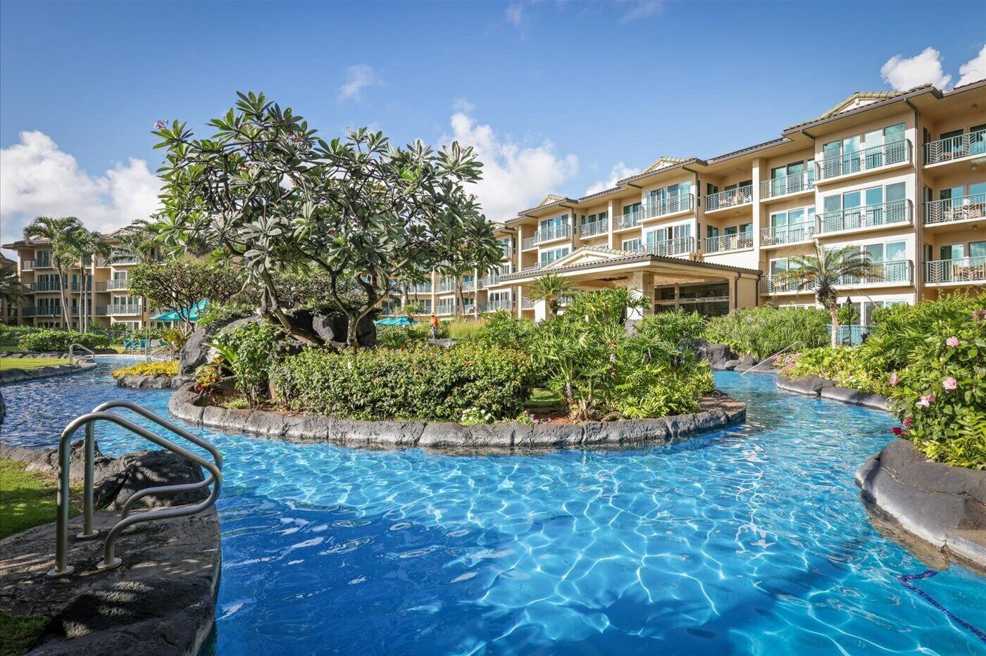 A hotel with a swimming pool, lush greenery, and a multi-story building with balconies.