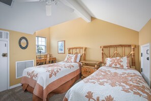 A bedroom with two beds, a desk, and a chair.