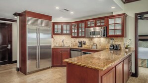 A modern kitchen with wooden cabinets, stainless steel appliances, and a granite countertop.