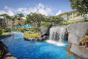 Un hotel con piscina, una cascada y un edificio con balcones.