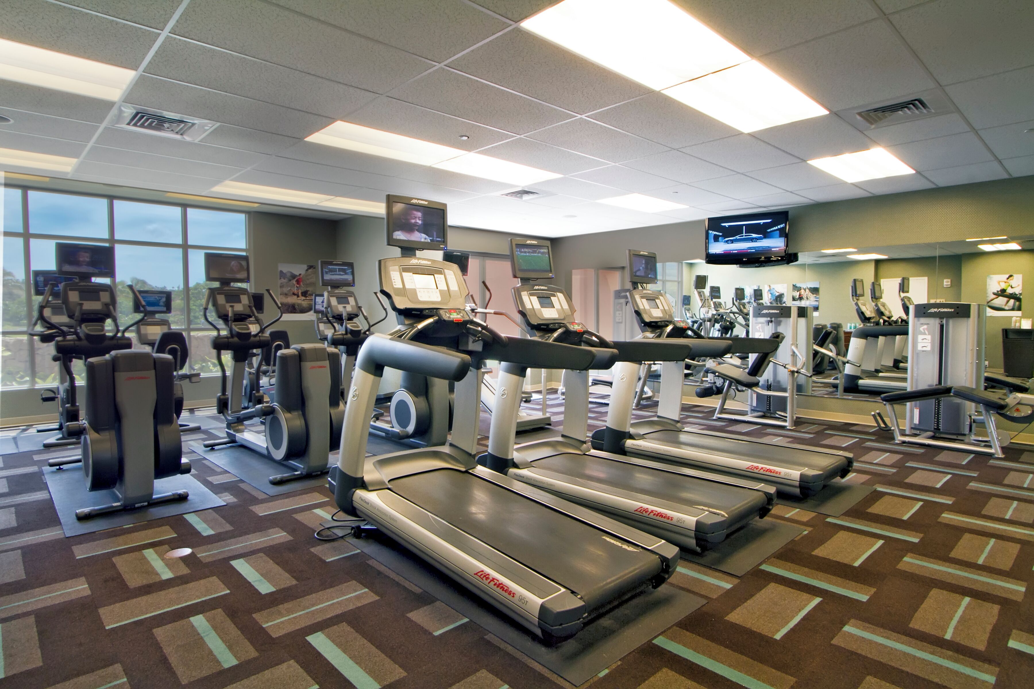 A gym with treadmills, elliptical machines, and weight stations.
