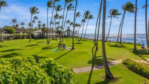 A golf course with a view of the ocean, surrounded by palm trees and buildings.