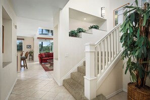 Un vaste espace de vie comprenant un escalier, un coin repas et une cuisine visible au fond.