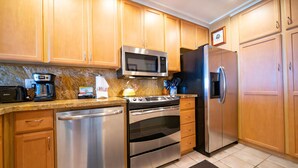 A modern kitchen with stainless steel appliances, wooden cabinets, and a marble countertop.