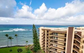 A multi-story hotel with balconies overlooking the ocean, a clear sky, and a view of the sea.