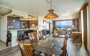 A spacious kitchen with a central island, a dining area with a glass table, and a view of the sea.