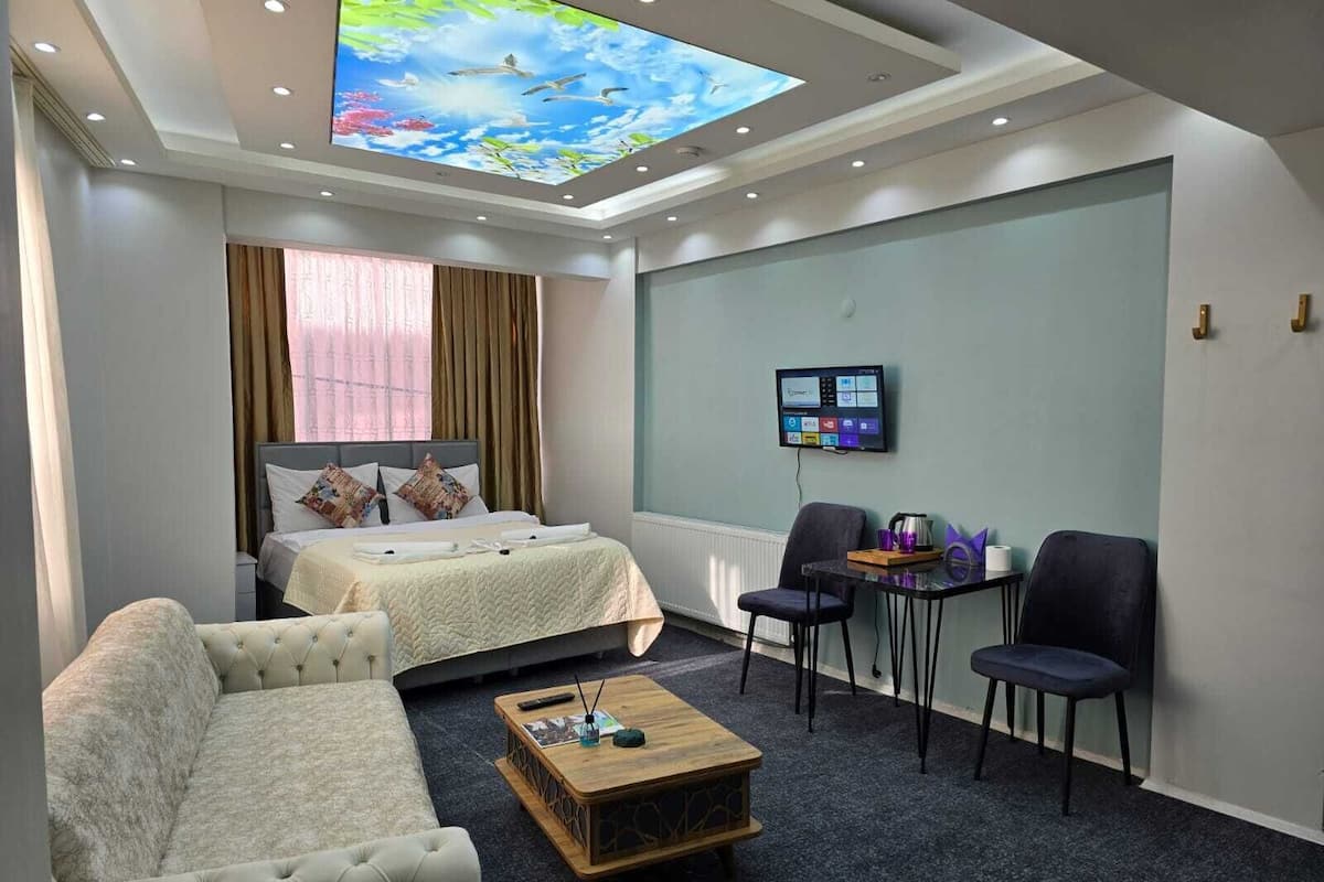 Une chambre d’hôtel équipée d’un lit, d’un canapé, d’une table basse et d’un téléviseur fixé au mur.