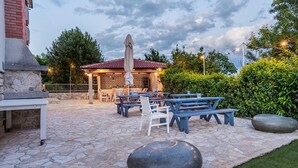 An outdoor patio area with stone flooring, picnic tables, and a covered seating area with umbrellas. - Beautiful apartment in Pula (Pula)