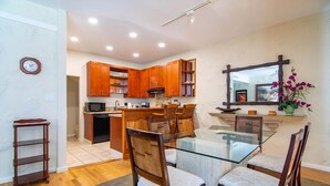 A modern kitchen with wooden cabinets, a glass dining table, and a built-in oven.