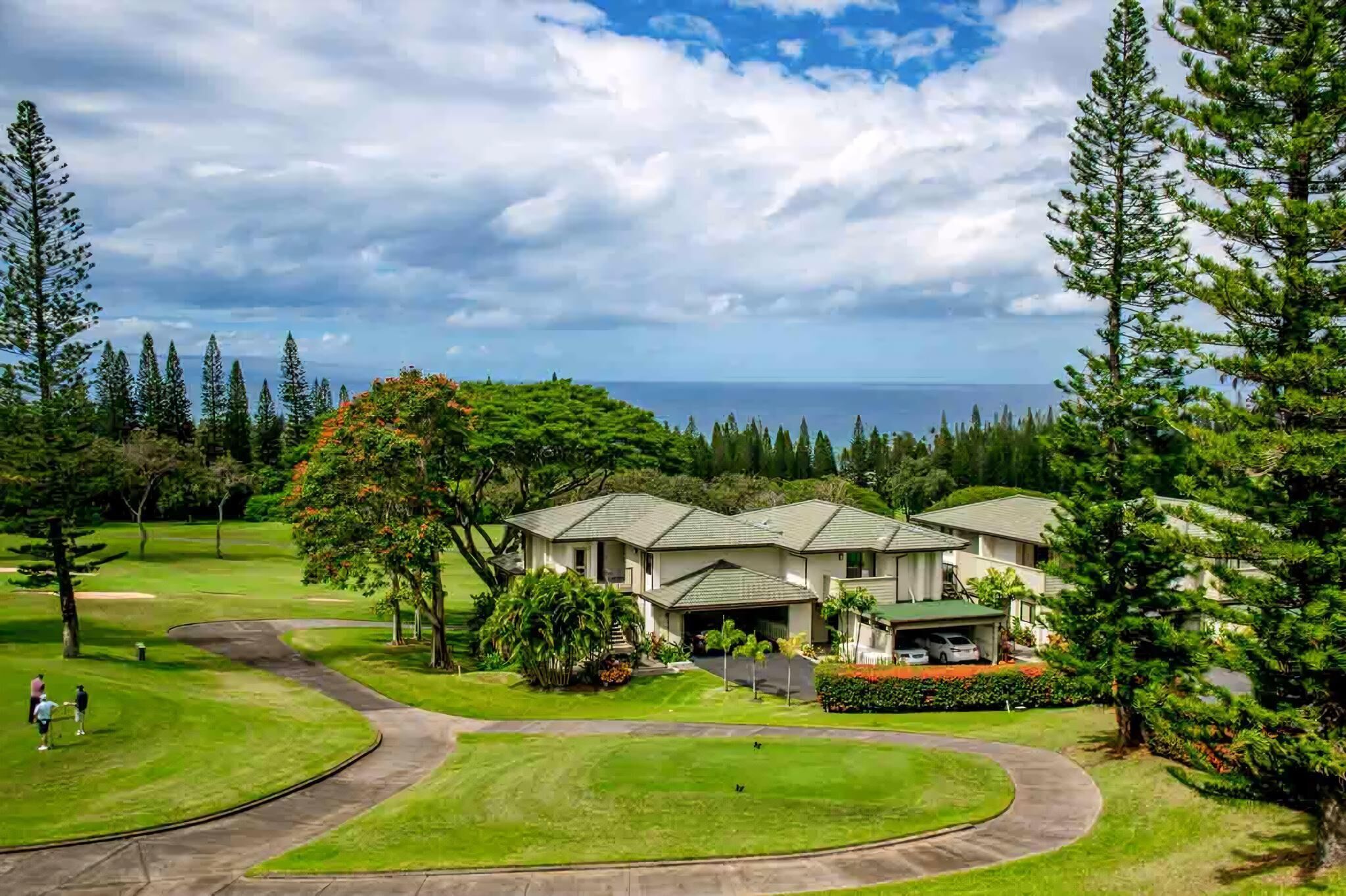 A golf course with a clubhouse and houses in the background.