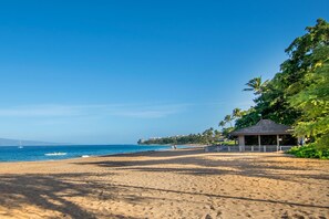 A beach with a gazebo, clear sky, and ocean.