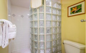 Ein Badezimmer mit Duschkabine aus Glas, Toilette und einem gerahmten Bild an der Wand.