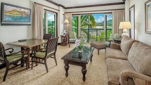 A hotel room with a balcony, a dining area, a sofa, and a TV.