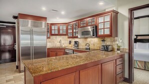 A kitchen with granite countertops, stainless steel appliances, wooden cabinetry, and a built-in microwave.