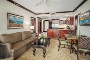 A living room with a sofa, coffee table, and chairs, a kitchen area with a bar, and a dining table.