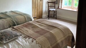 Un dormitorio con dos camas, una puerta de madera, una ventana con cortinas y una silla.