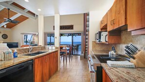 Una cocina con armarios de madera, encimeras de granito, lavavajillas y vistas al exterior.