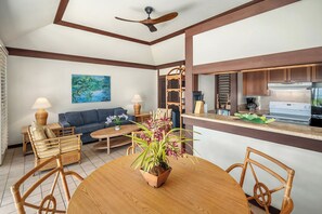 Uma sala de estar moderna com sofá, mesa de jantar, cadeiras e uma cozinha com fogão e armários.