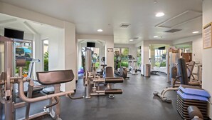 A gym with various exercise machines, a bench, and a mirror.