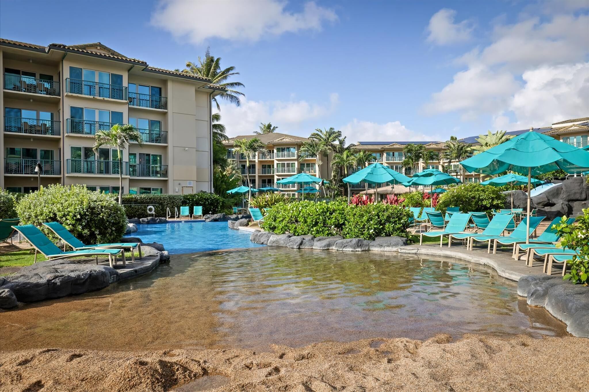 A resort pool area with clear water, lounge chairs, and umbrellas.